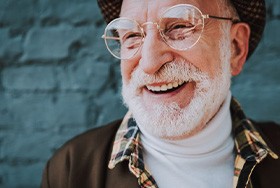 Smiling man in fashionable outfit on blue brick background