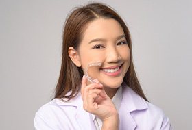 Smiling patient holding clear aligner
