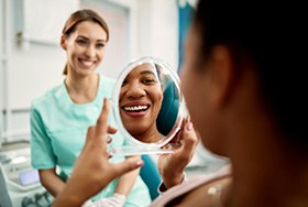 Patient smiling at reflection in treatment chair