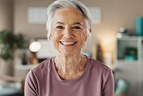 Woman with gray hair smiling in a beige room