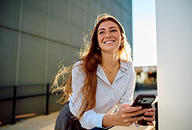 a smiling woman holding her phone in her hands