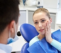 Woman in dental chair holding cheek