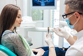 Dentist showing patient dental implant model