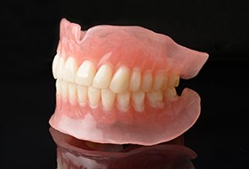 Profile view of a full set of dentures on a reflective black surface