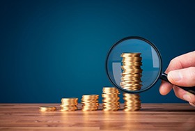 Magnifying glass examining a stack of coins 