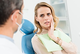 Woman in dental chair holding jaw