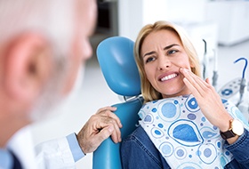 Woman in dental chair holding cheek