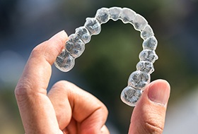 Hand holding clear Invisalign tray