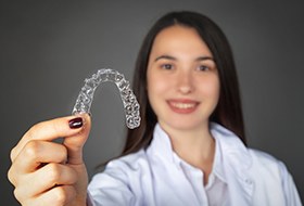 Woman holding up Invisalign tray