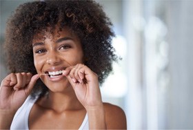 Woman smiling while flossing her teeth