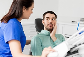 Man in dental chair holding cheek