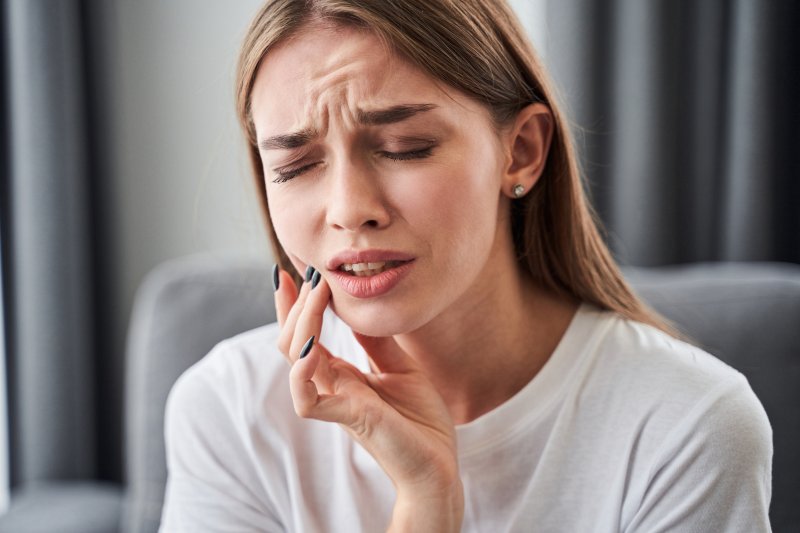 girl in pain touching her cheek with fingers