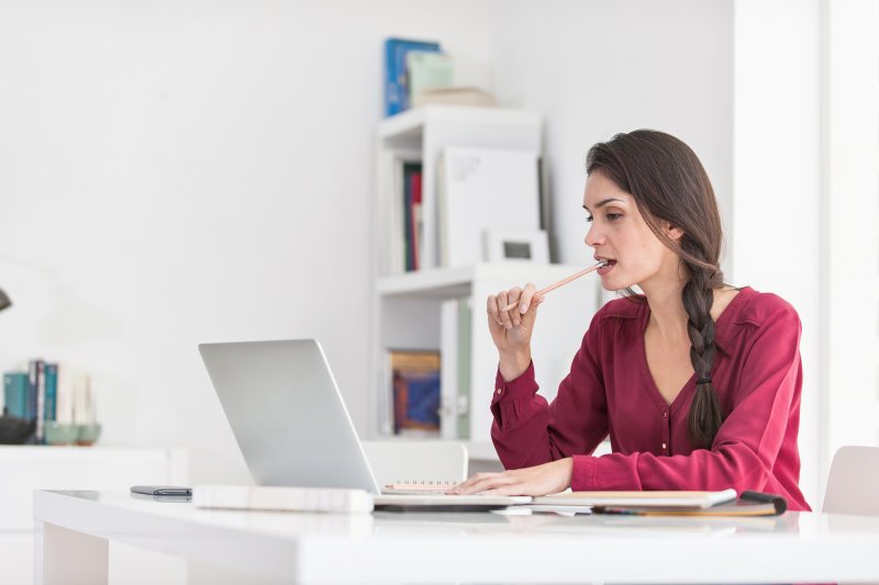 woman chewing on pencil while working