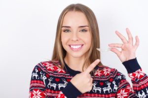 woman holding Invisalign aligner in holiday attire