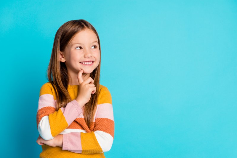 Child smiling and pondering on blue background