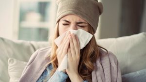 woman with the flu blowing her nose