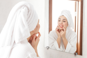 a woman inspecting her teeth in her bathroom mirror