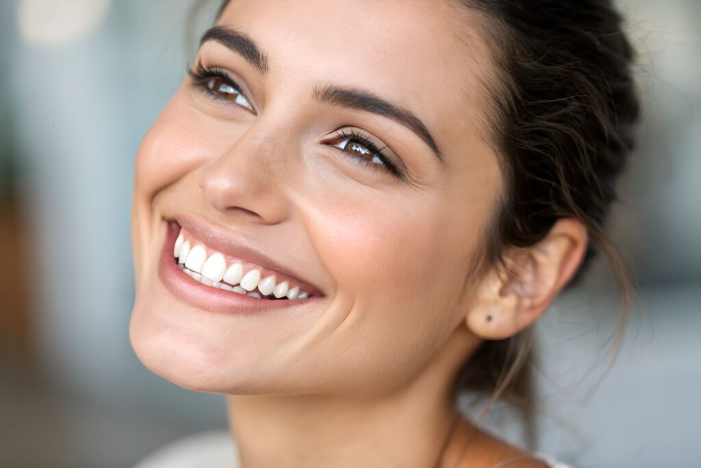 Facial closeup of woman with brown hair and eyes smiling