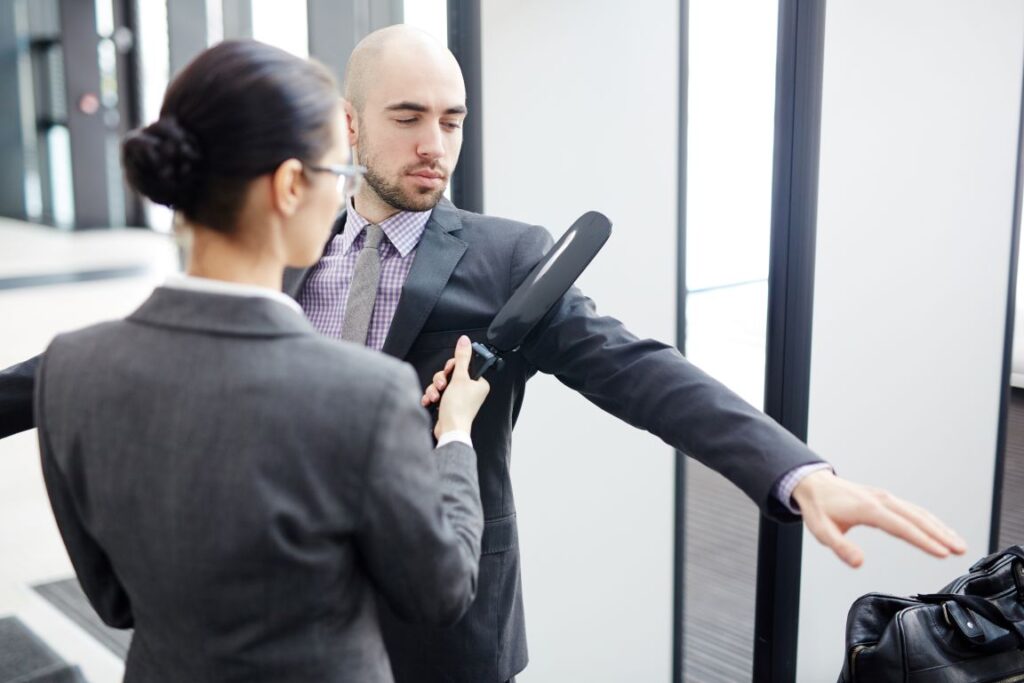 A man being scanned with a metal detector at airport security.